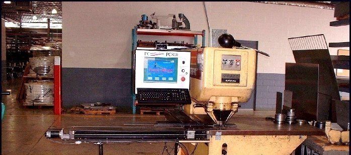 Industrial machine with a monitor and control panel in a workshop, with equipment on a metal table