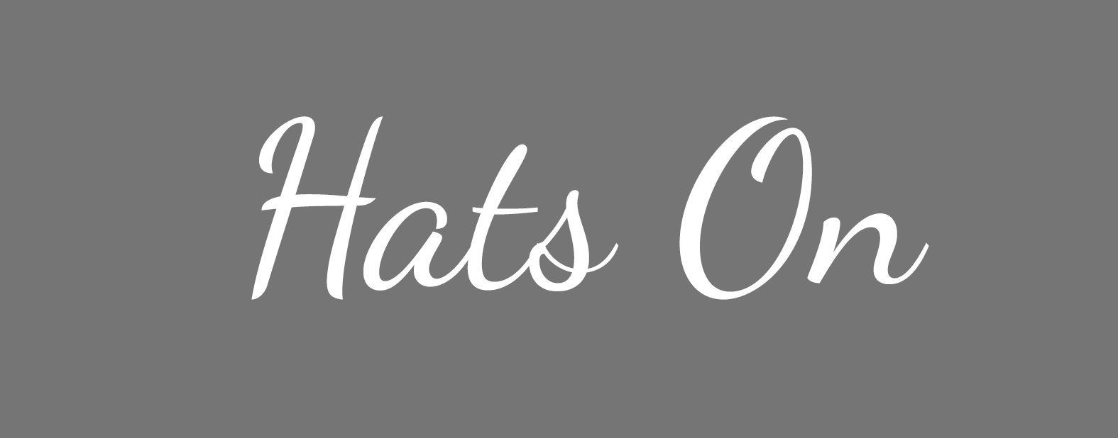White script text “Hats On” on a gray background