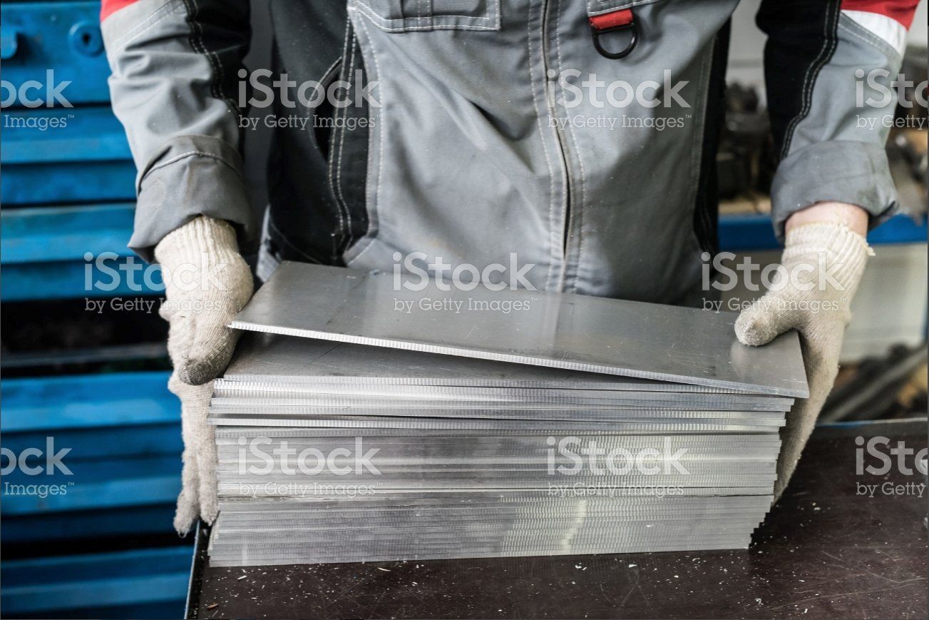 Gloved worker holding a stack of folded newspapers beside a blue delivery truck