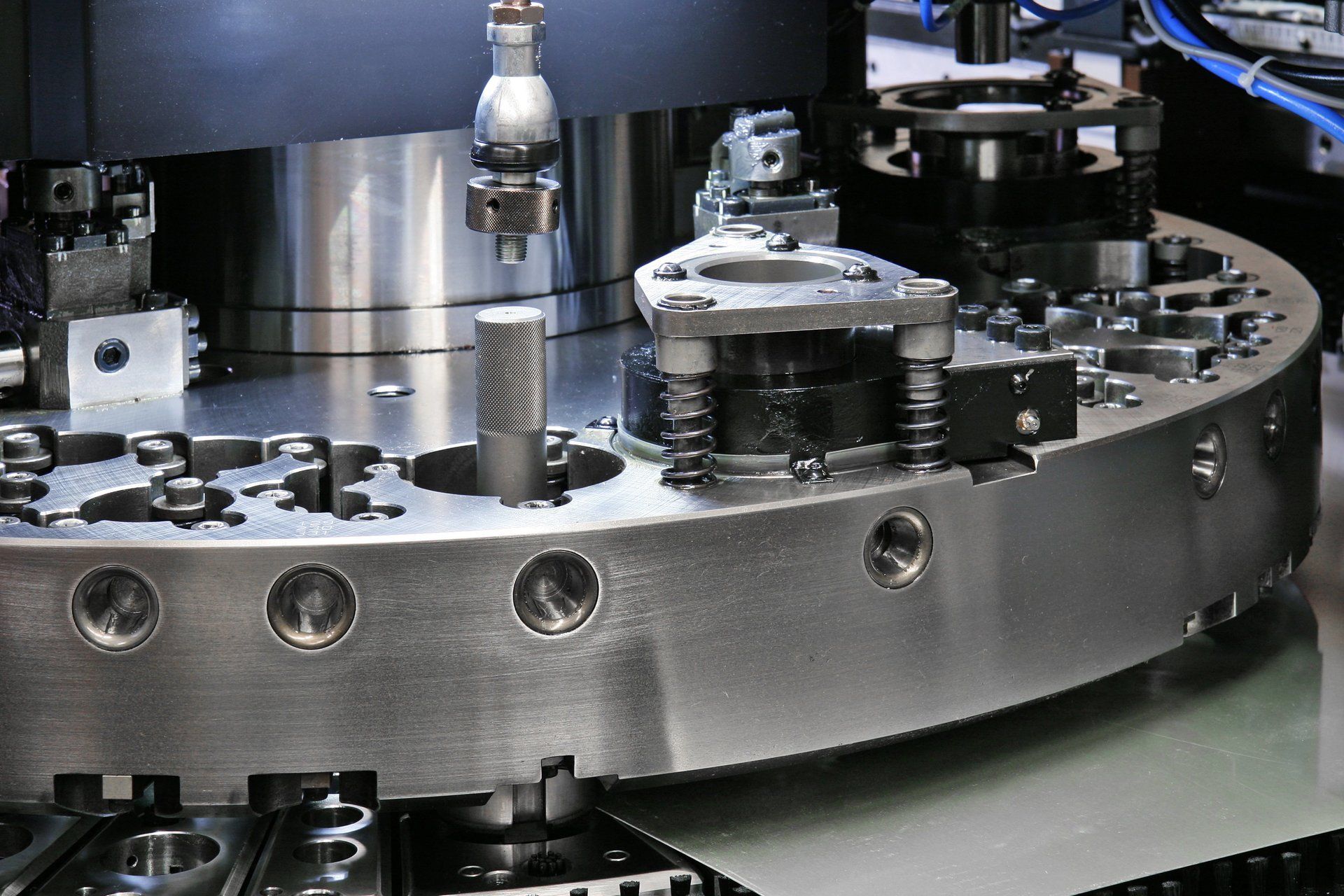 Close-up of an industrial metal machine with rotating parts and bolts in a factory setting