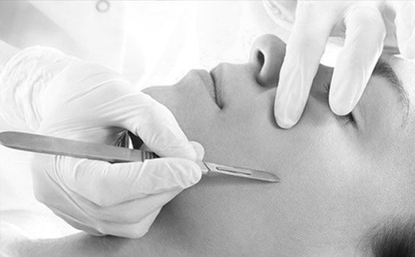 A black and white photo of a person getting a facial treatment with a scalpel.
