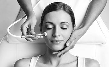 A woman is getting a facial treatment in a black and white photo.