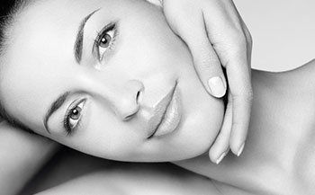 A woman is touching her face in a black and white photo.