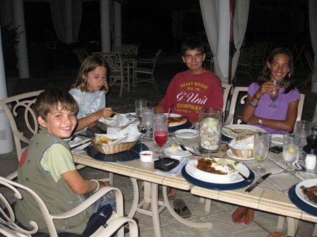 A boy wearing a g unit shirt sits at a table with his friends