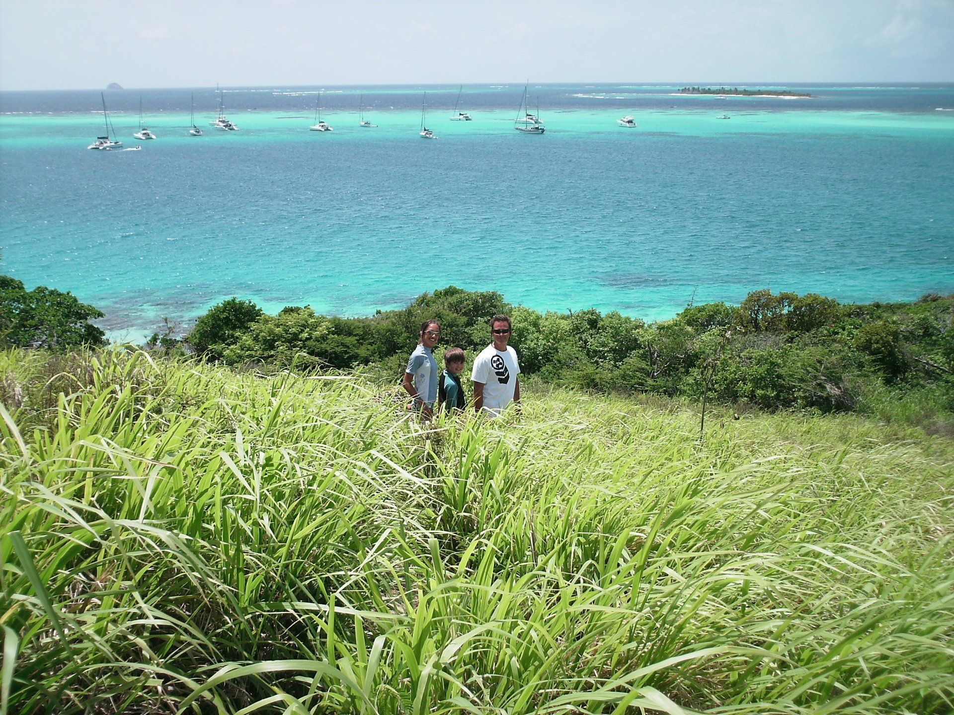 A group of people standing in a field with the ocean in the background