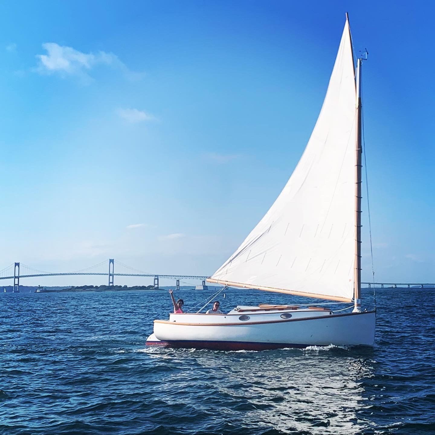 A sailboat in the ocean with a bridge in the background