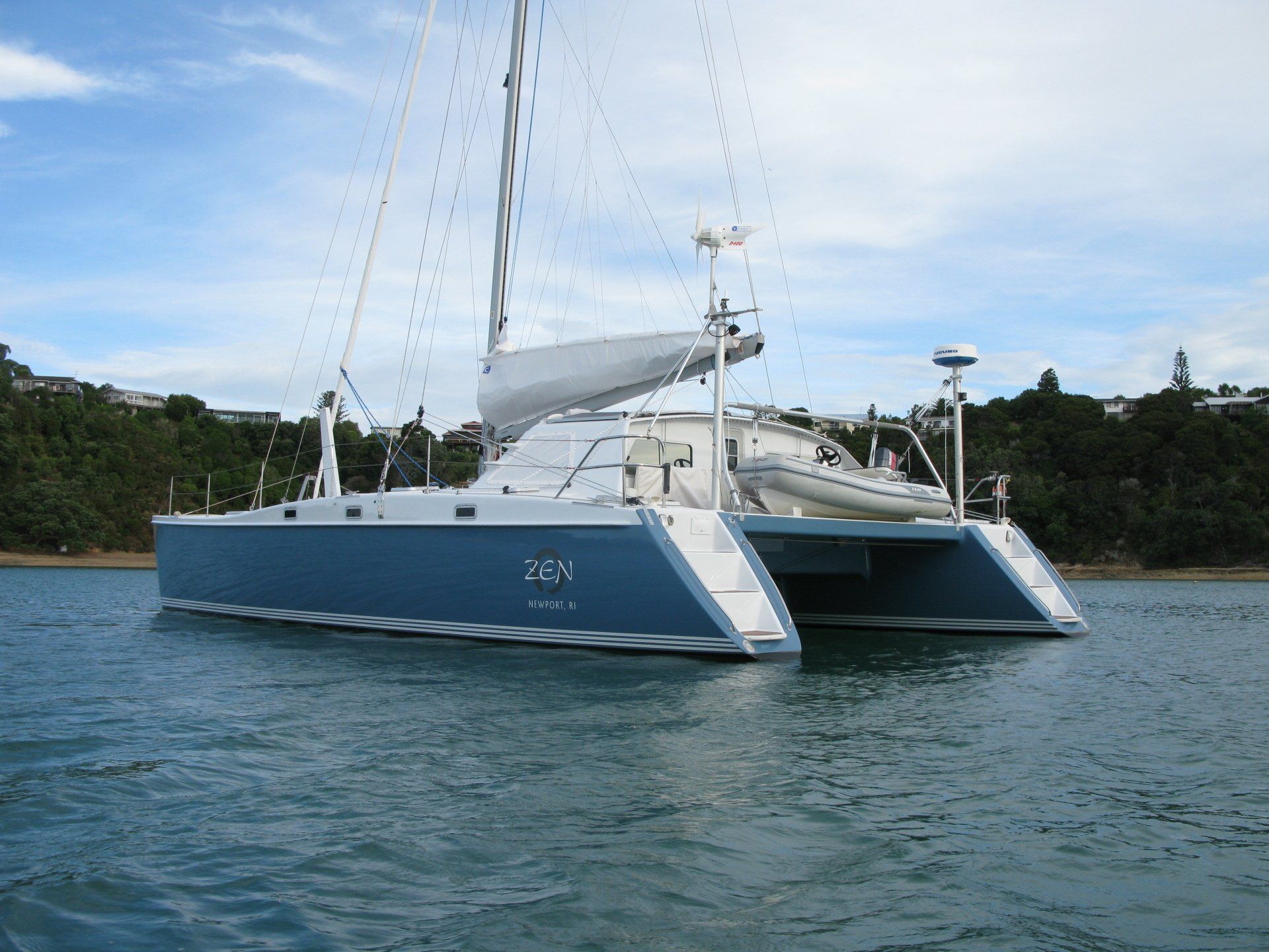 A blue and white sailboat is floating in the water
