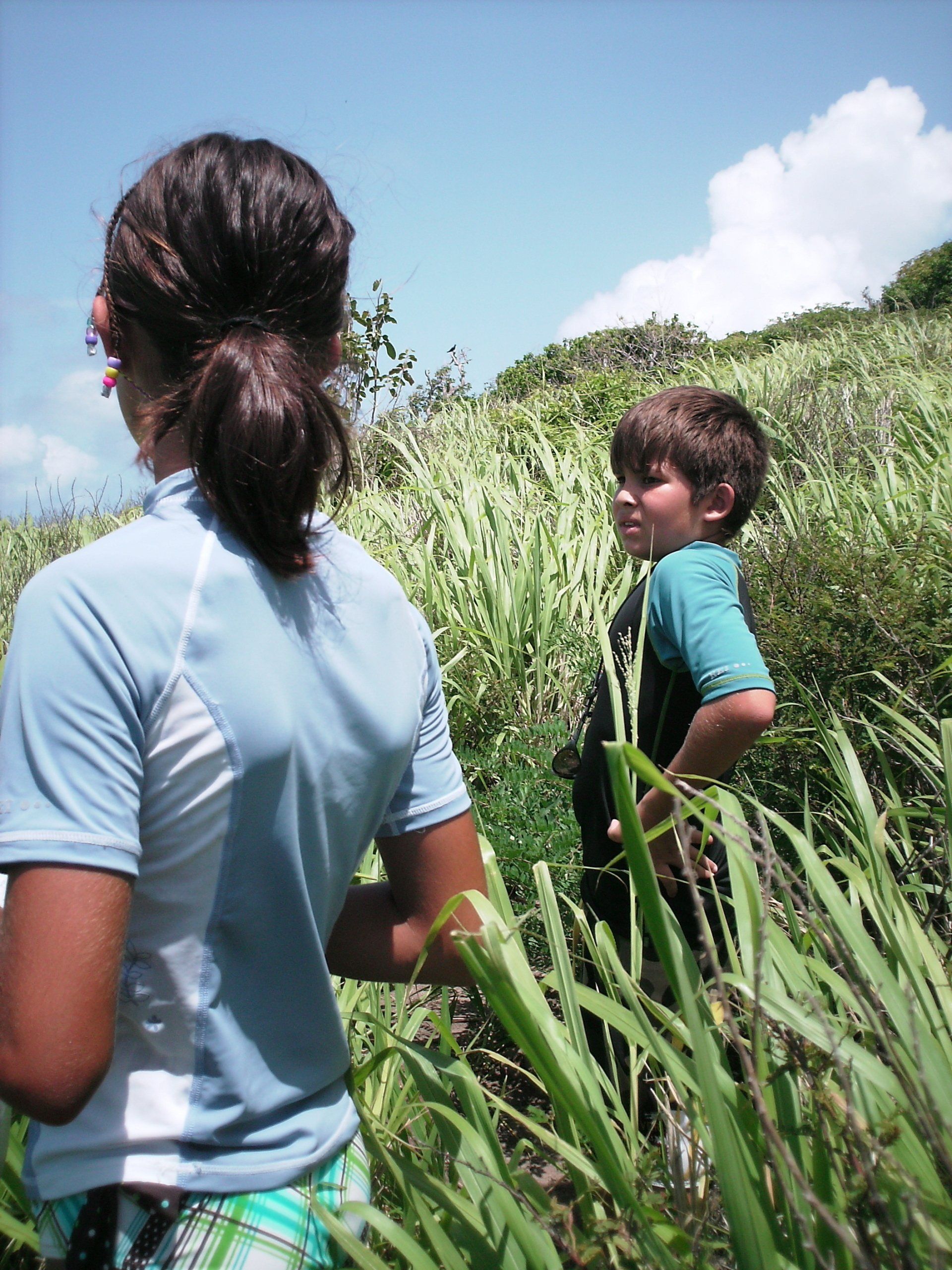 A boy and a girl are standing in a field of tall grass