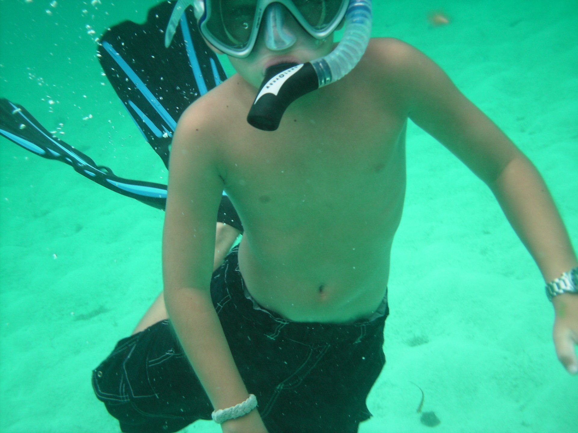 A young boy wearing a mask and goggles is swimming in the ocean