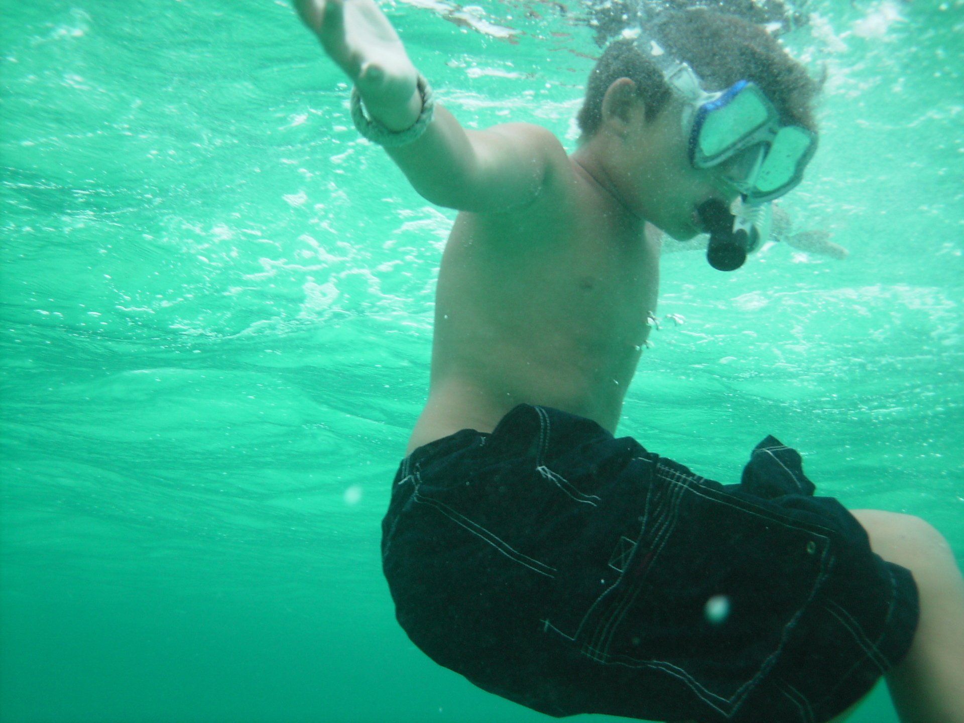 A young boy wearing a mask and goggles is swimming underwater