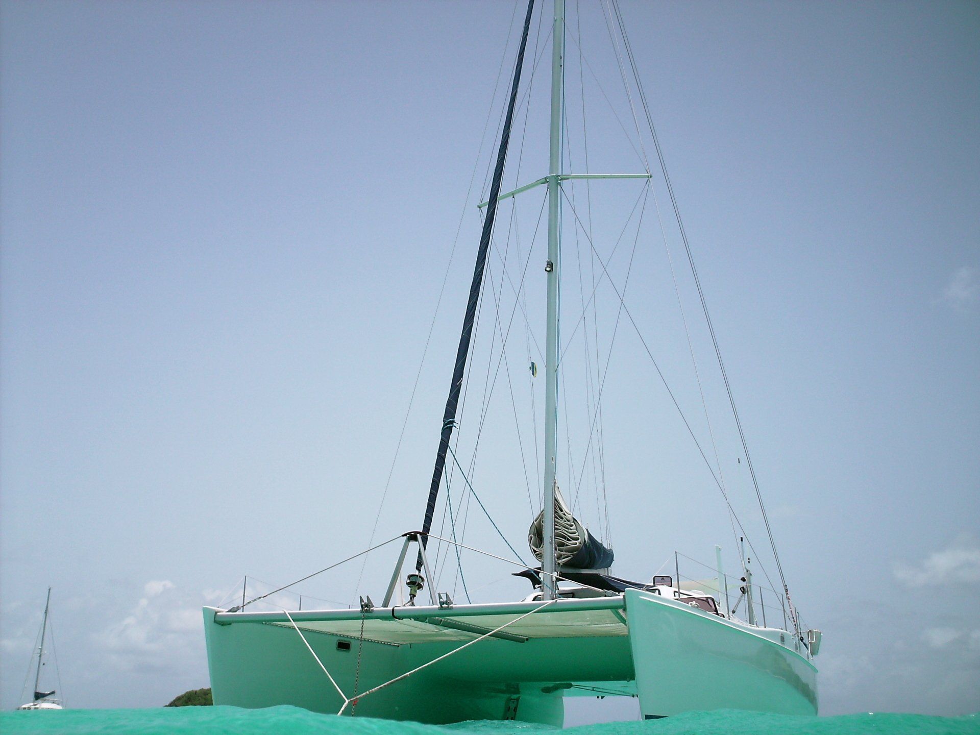 A green sailboat is floating on top of a body of water