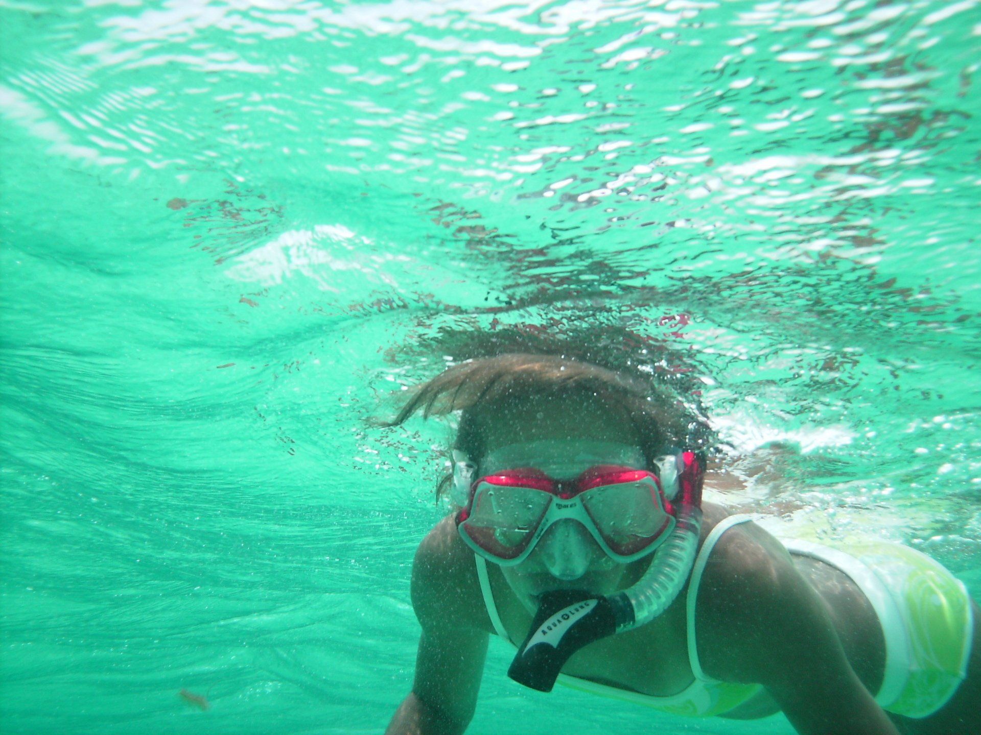 A woman wearing a mask and goggles is swimming underwater