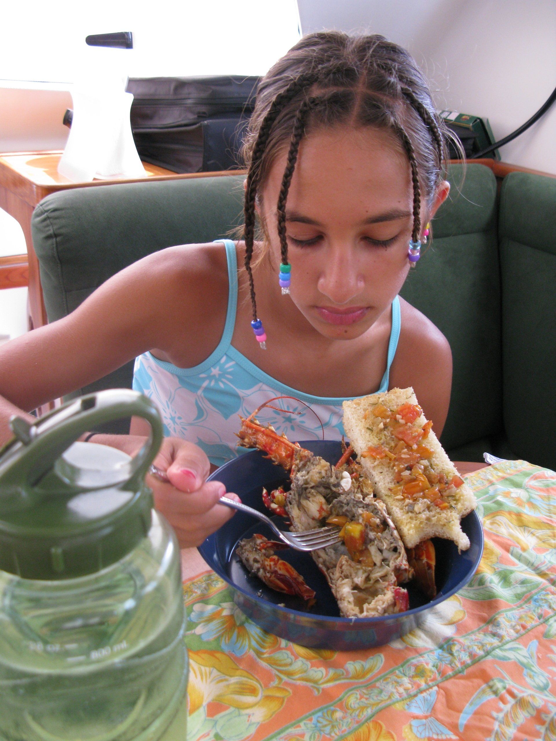 A young girl is sitting at a table eating a bowl of food