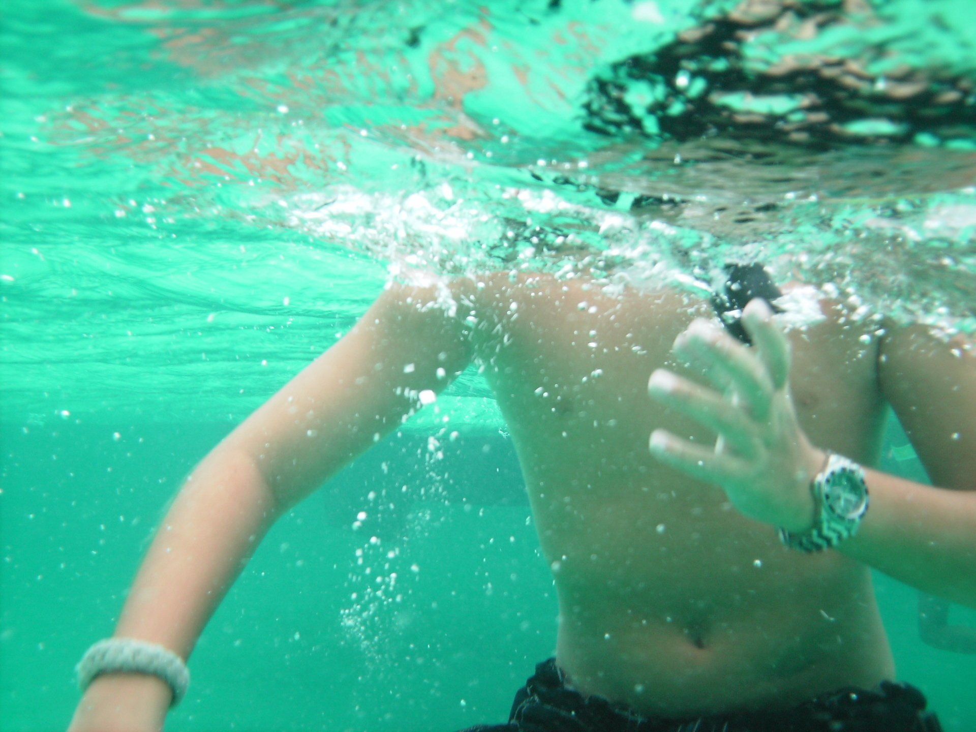 A man wearing a watch is swimming underwater