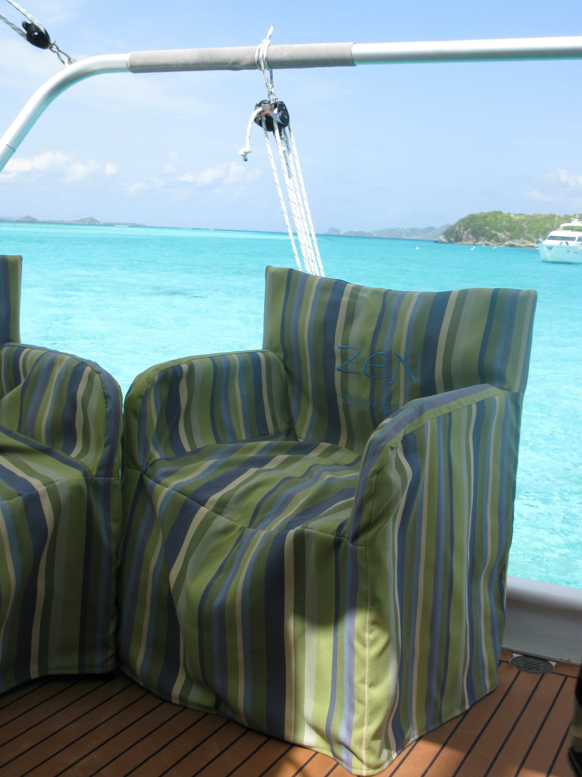 Two striped chairs on a boat with the ocean in the background