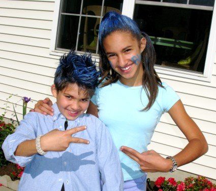 A boy with blue hair is standing next to a girl with blue paint on her face