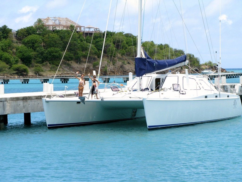 A white sailboat with a blue sail is docked at a dock