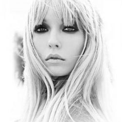 A black and white photo of a woman with long blonde hair and bangs.