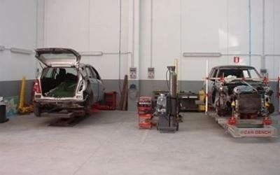 Due auto in riparazione in un'officina di carrozzeria, con attrezzi e attrezzature tra di esse.