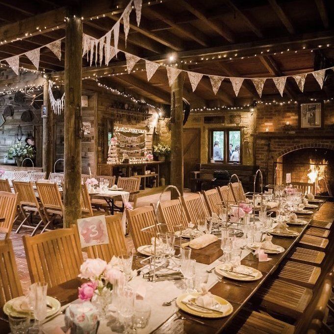 A long wooden table with plates , glasses , and flowers on it.