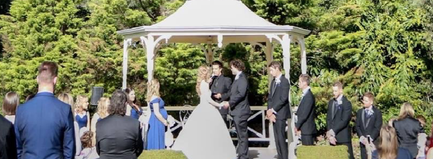 A bride and groom are getting married in front of a gazebo.