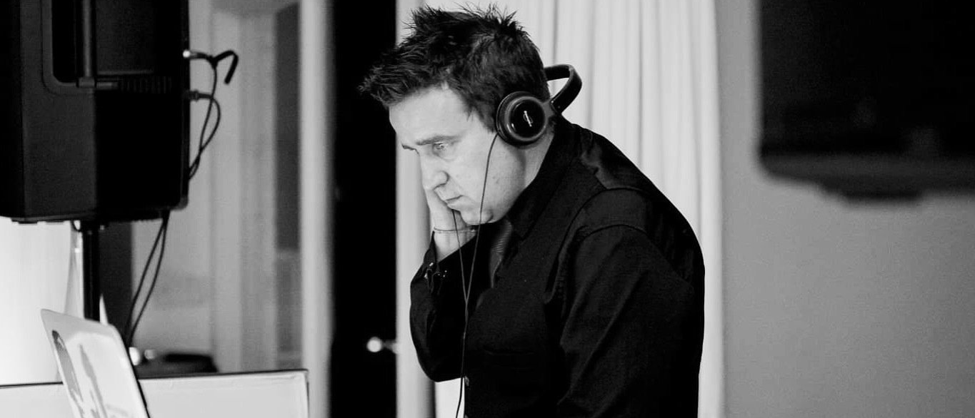 A man wearing headphones is talking on a cell phone in a black and white photo.