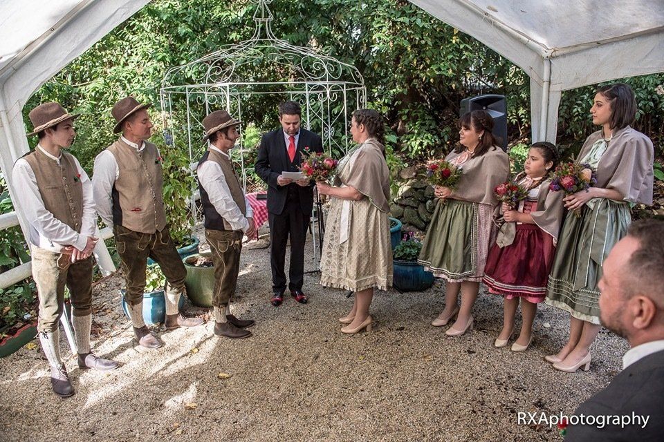 A group of people are standing under a tent holding flowers.