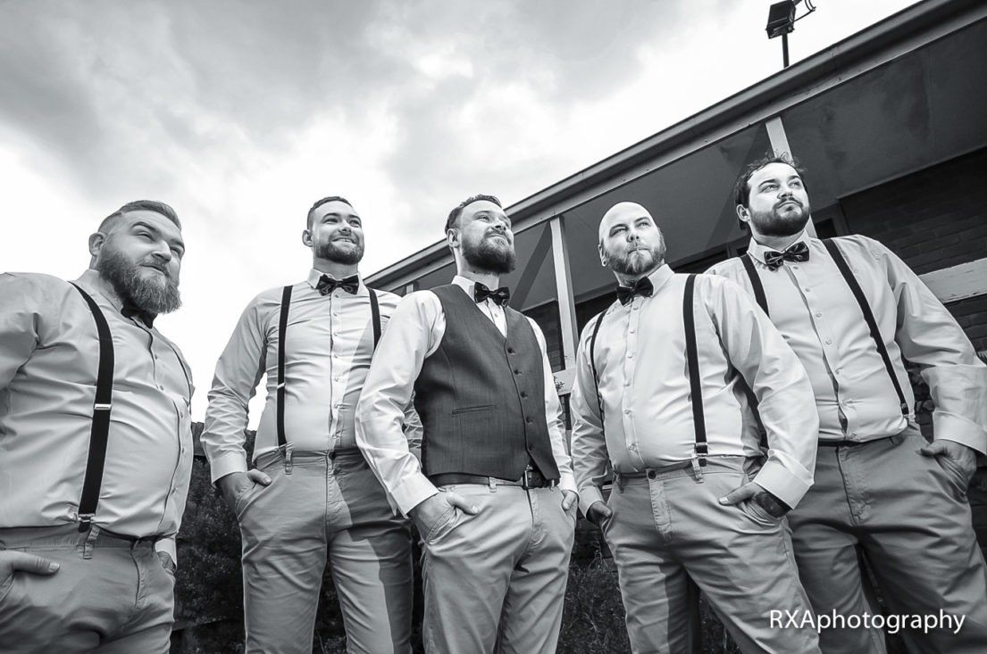A group of men standing next to each other wearing suspenders and bow ties.