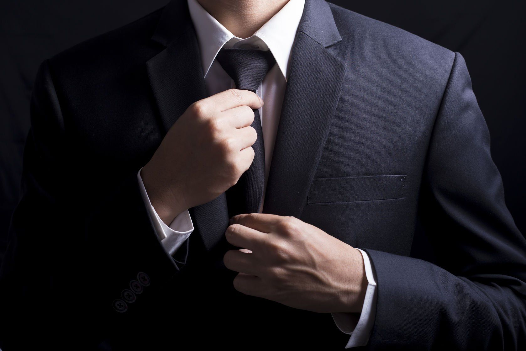 A man in a suit is adjusting his tie