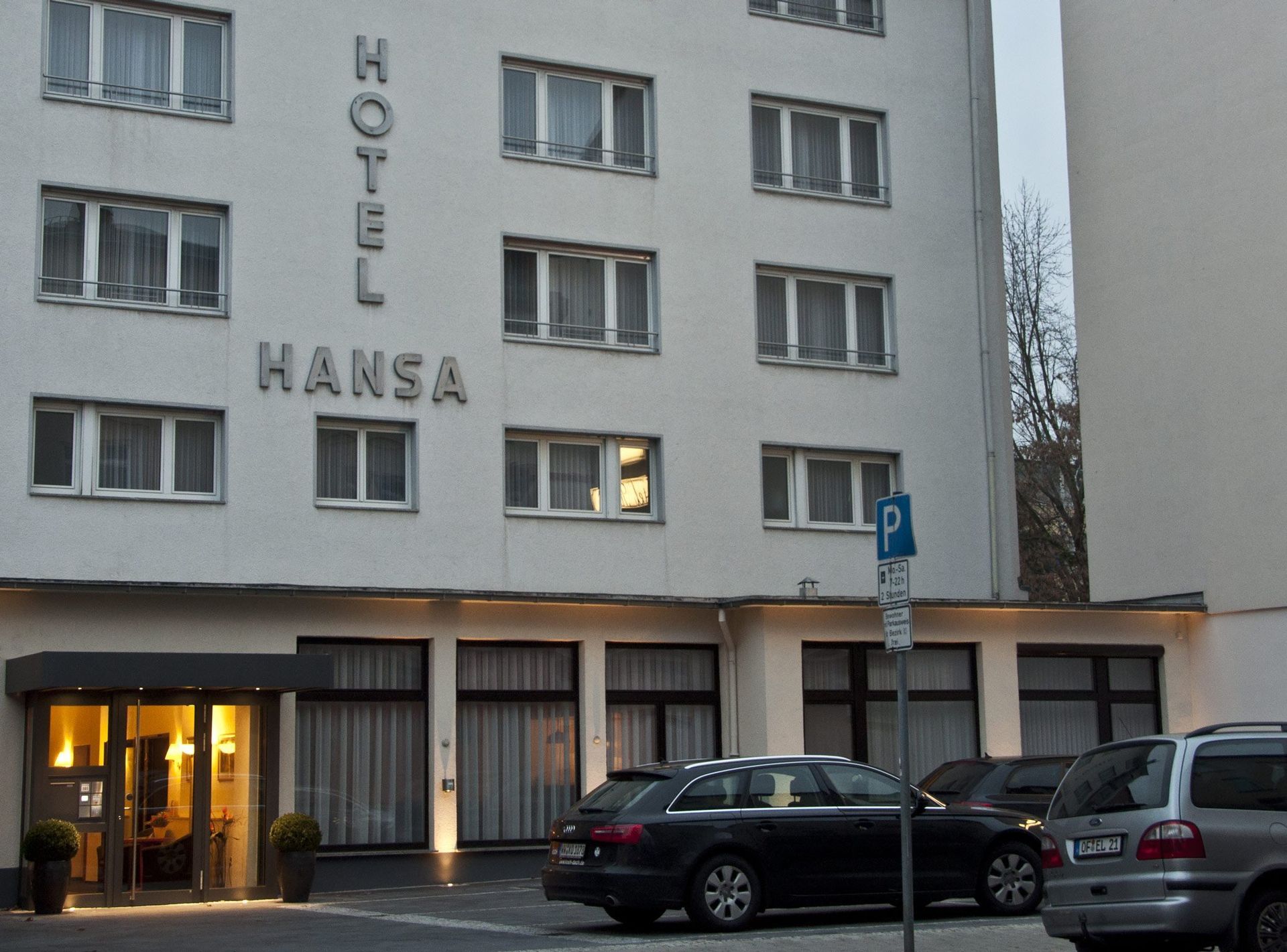 A hansa hotel with cars parked in front of it