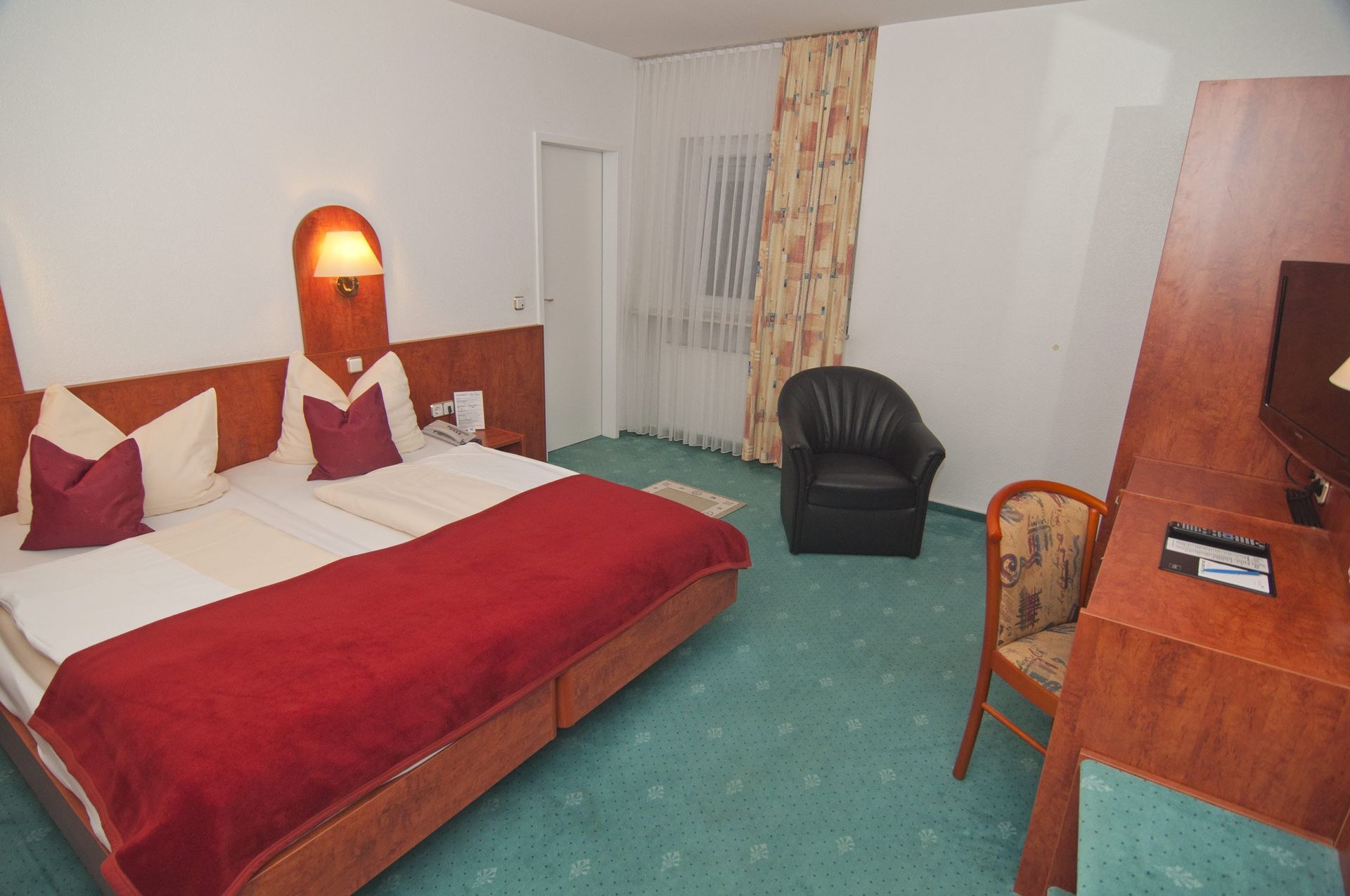 Ein Hotelzimmer mit zwei Betten, einem Stuhl und einem Schreibtisch.