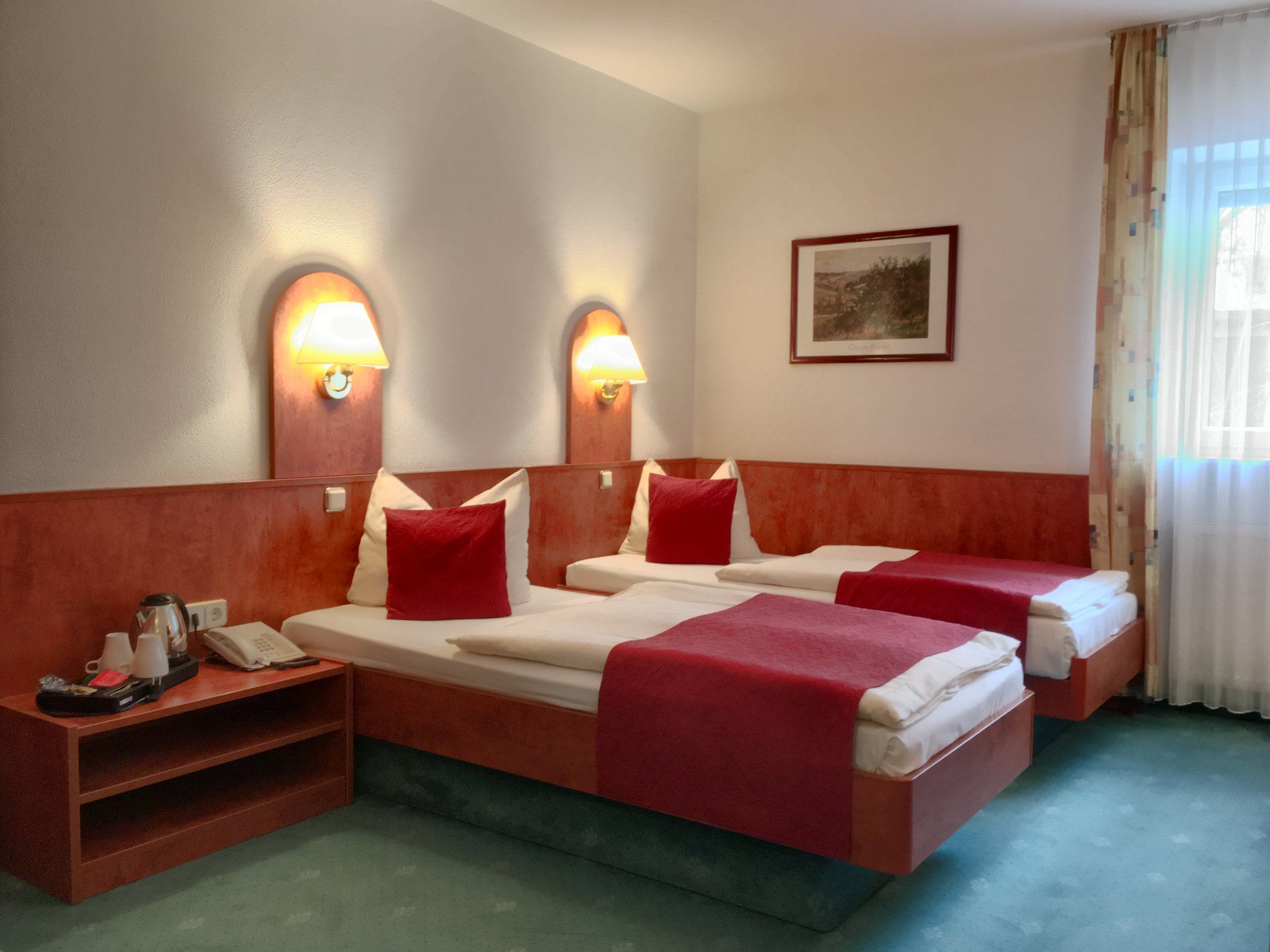 Ein Hotelzimmer mit zwei Betten und einem Bild an der Wand.