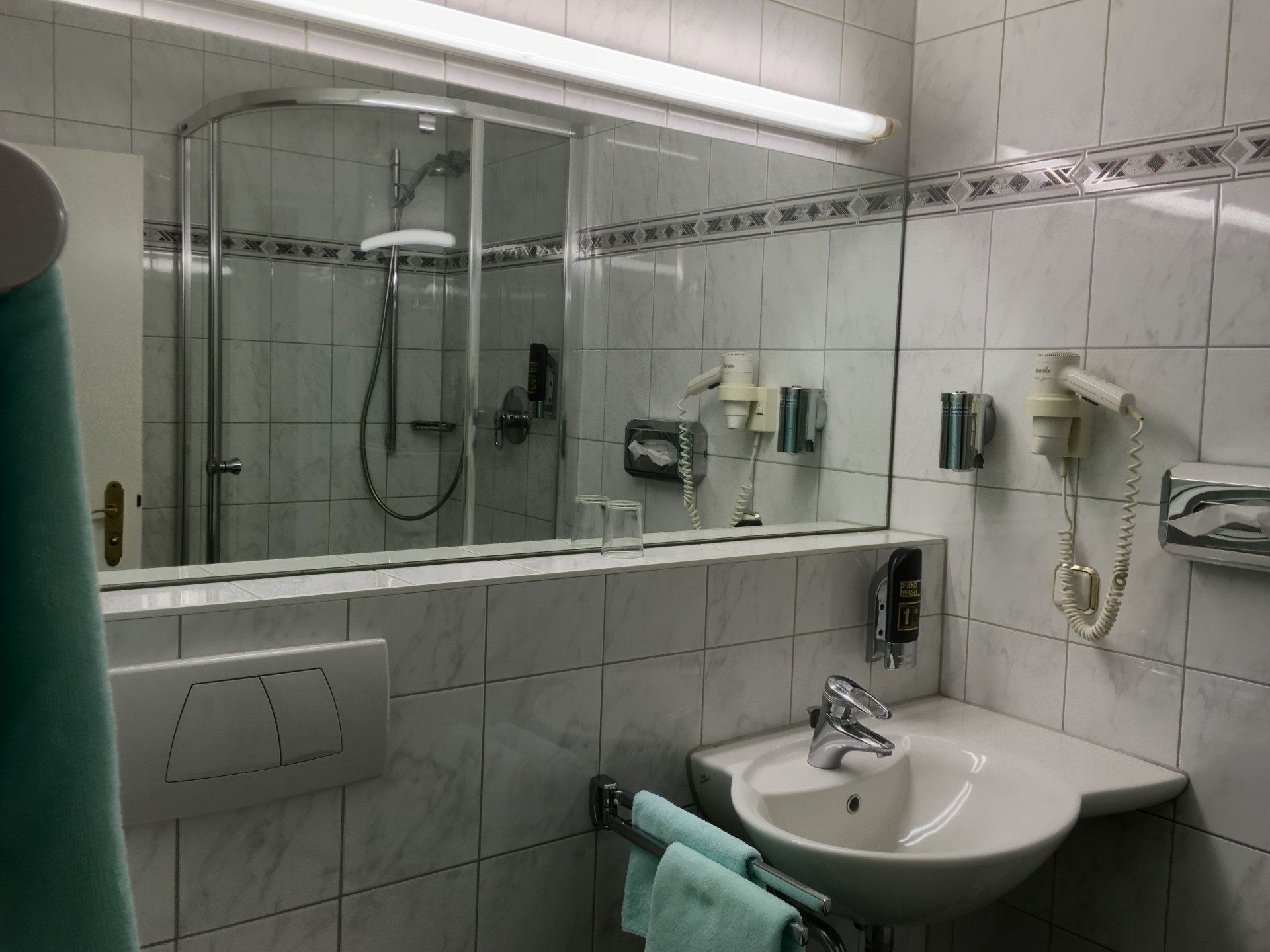Ein Badezimmer mit Waschbecken, Dusche, Spiegel und Haartrockner.