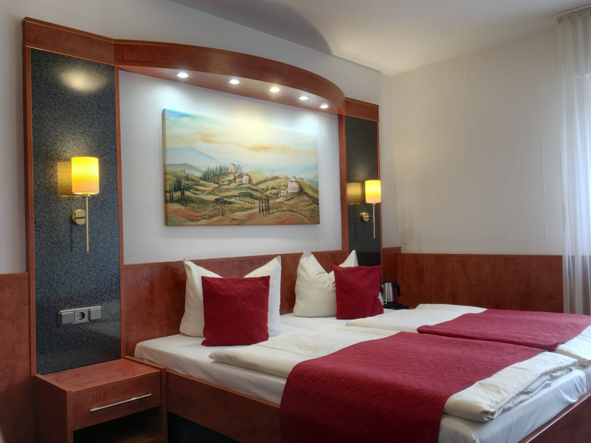 Ein Hotelzimmer mit zwei Betten und einem Gemälde an der Wand.