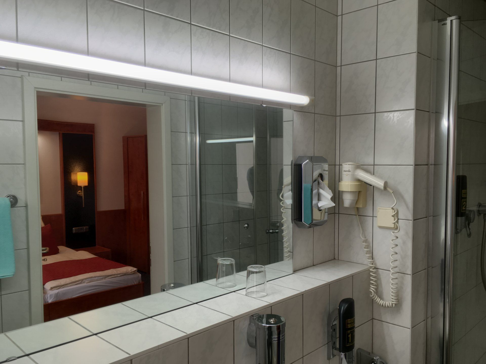 Ein Badezimmer mit großem Spiegel und Haartrockner