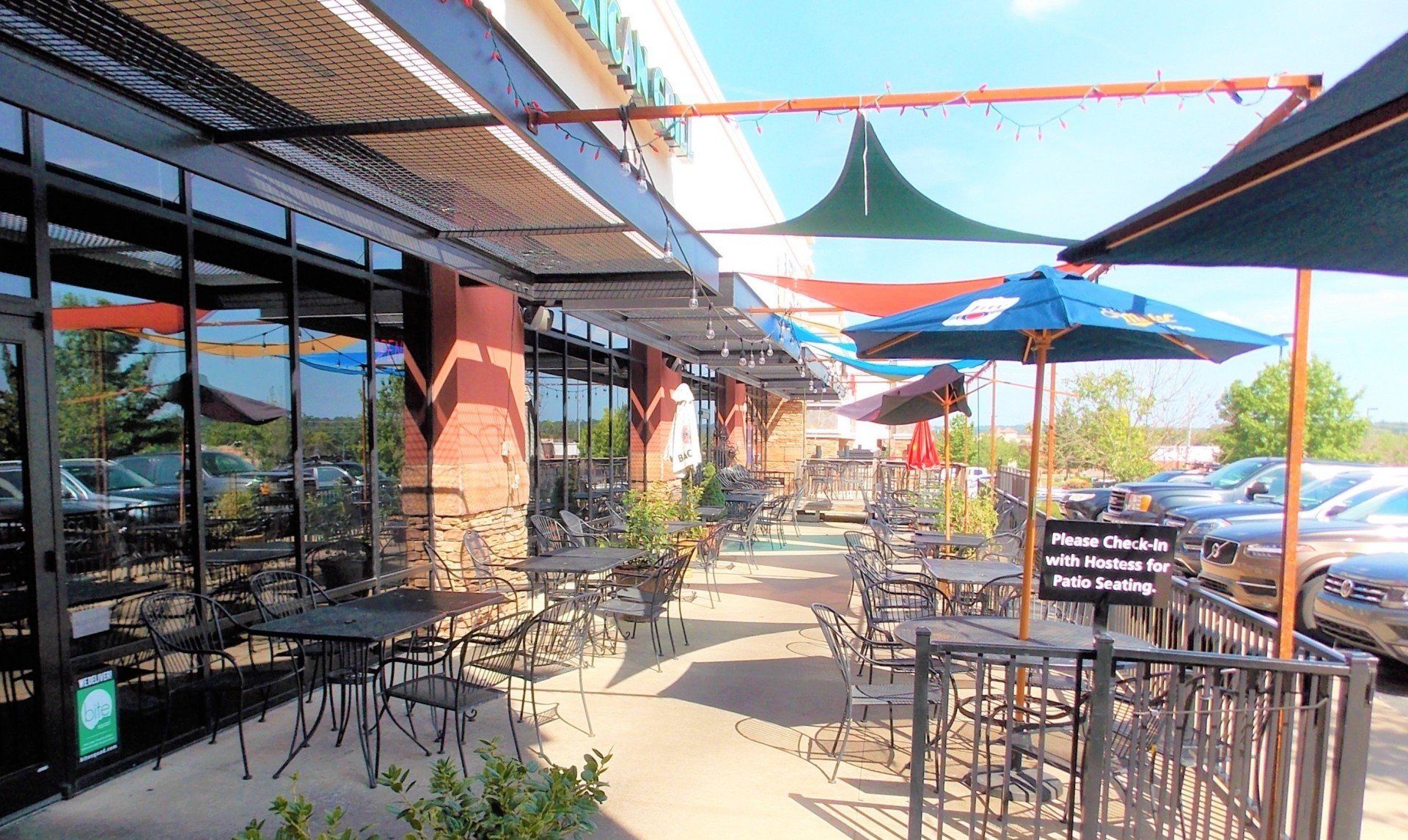 Outdoor restaurant seating area with tables, umbrellas, and awnings.