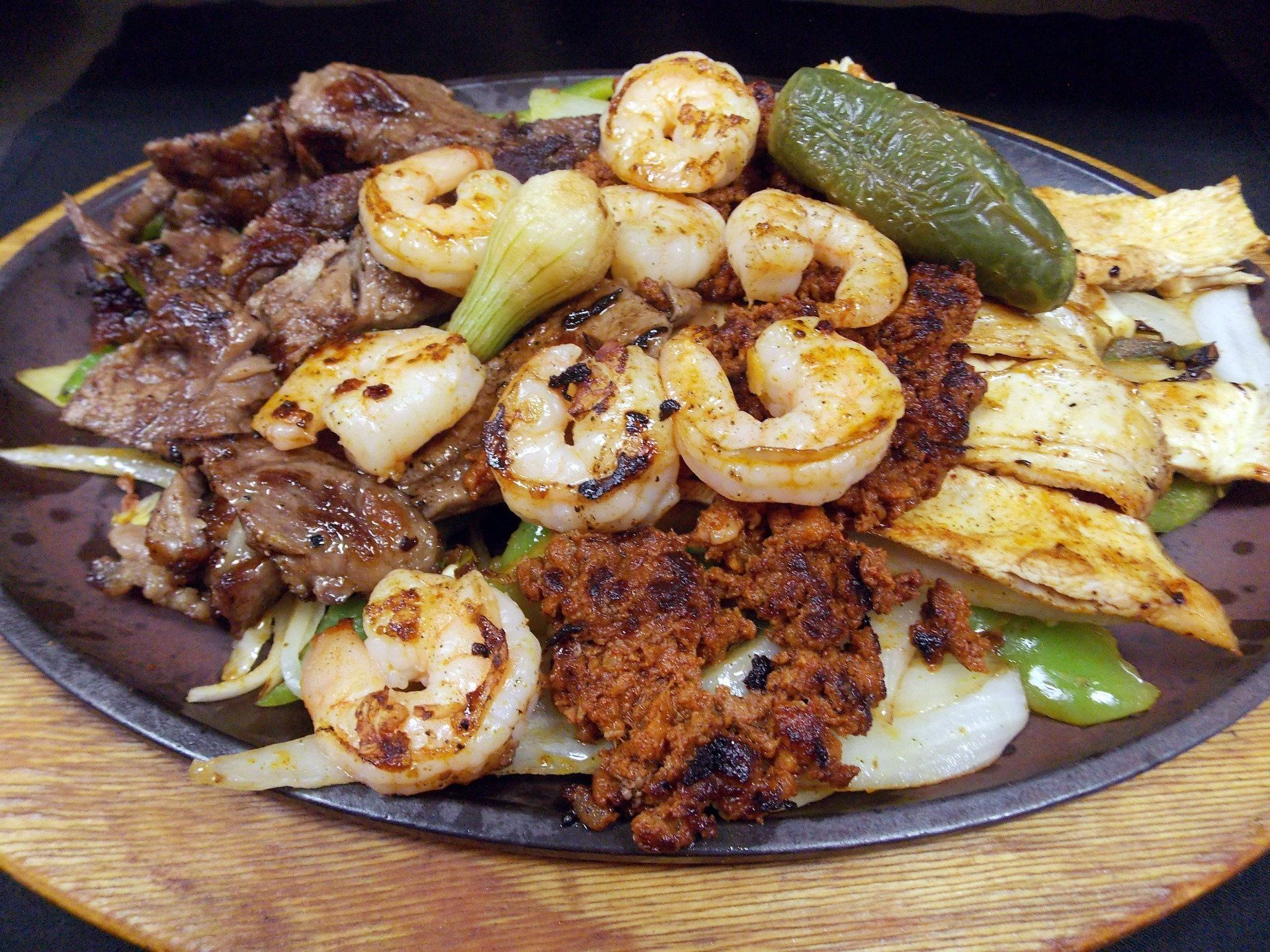 Sizzling platter with grilled steak, shrimp, chicken, chorizo, and jalapeno pepper.