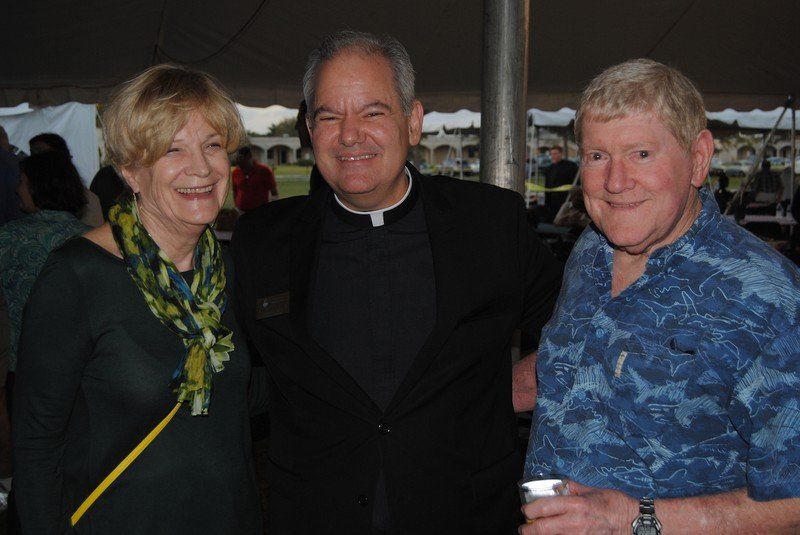 Priest and two guests smiling for the camera.