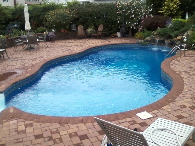 a large swimming pool is surrounded by bricks and chairs
