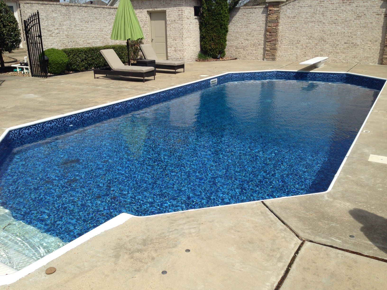 a large blue swimming pool with a green umbrella