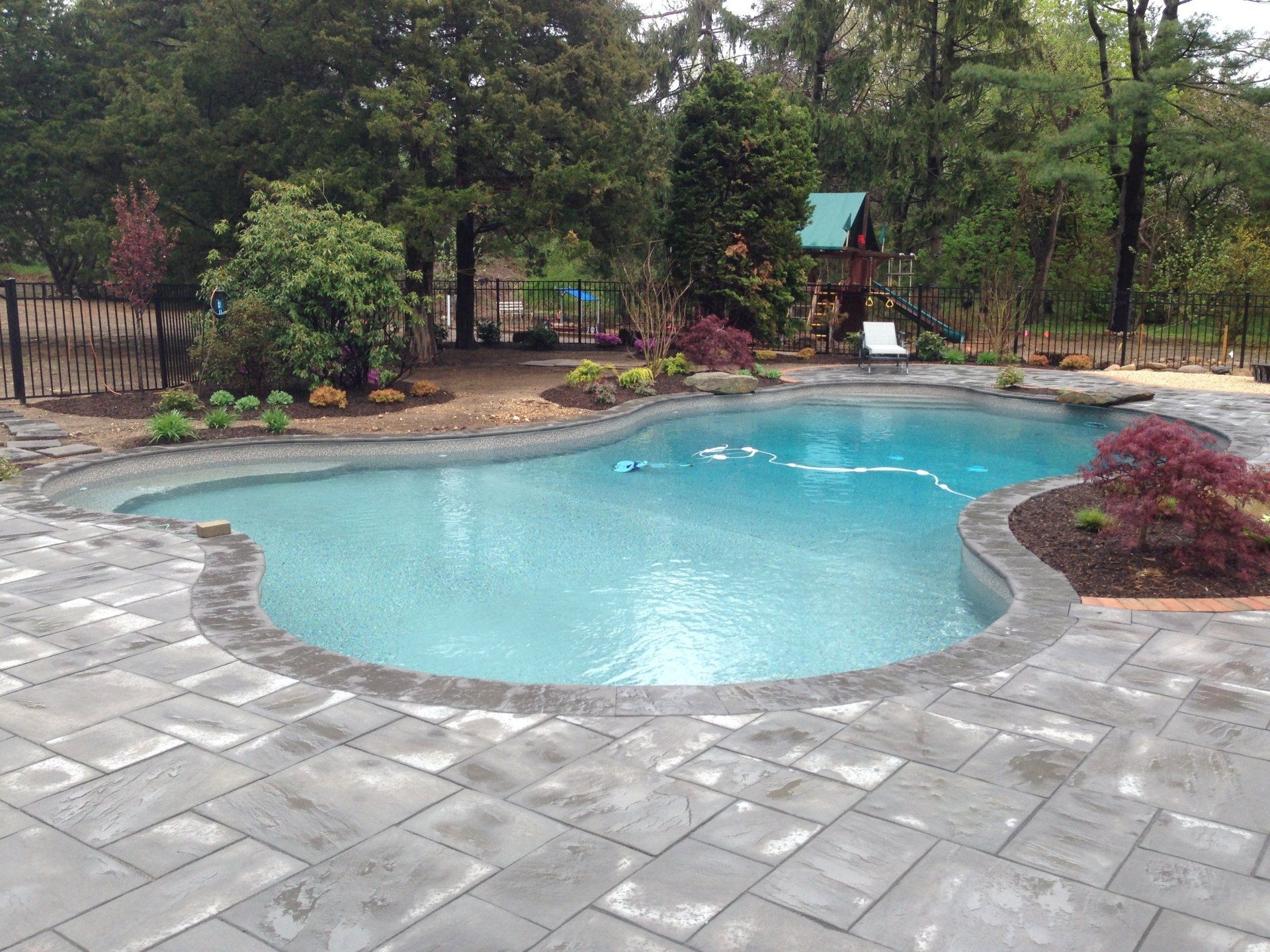 a large swimming pool surrounded by trees and a fence