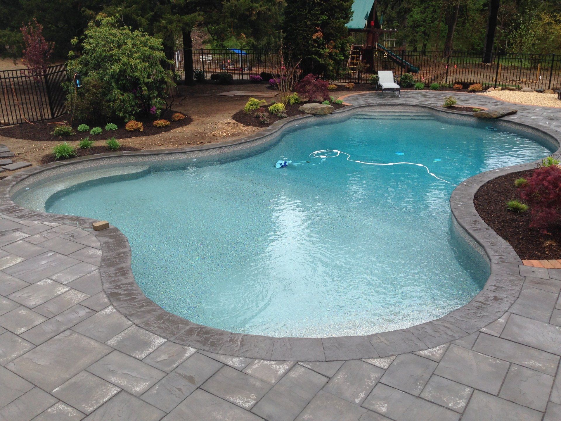 a large swimming pool is surrounded by a fence and a patio