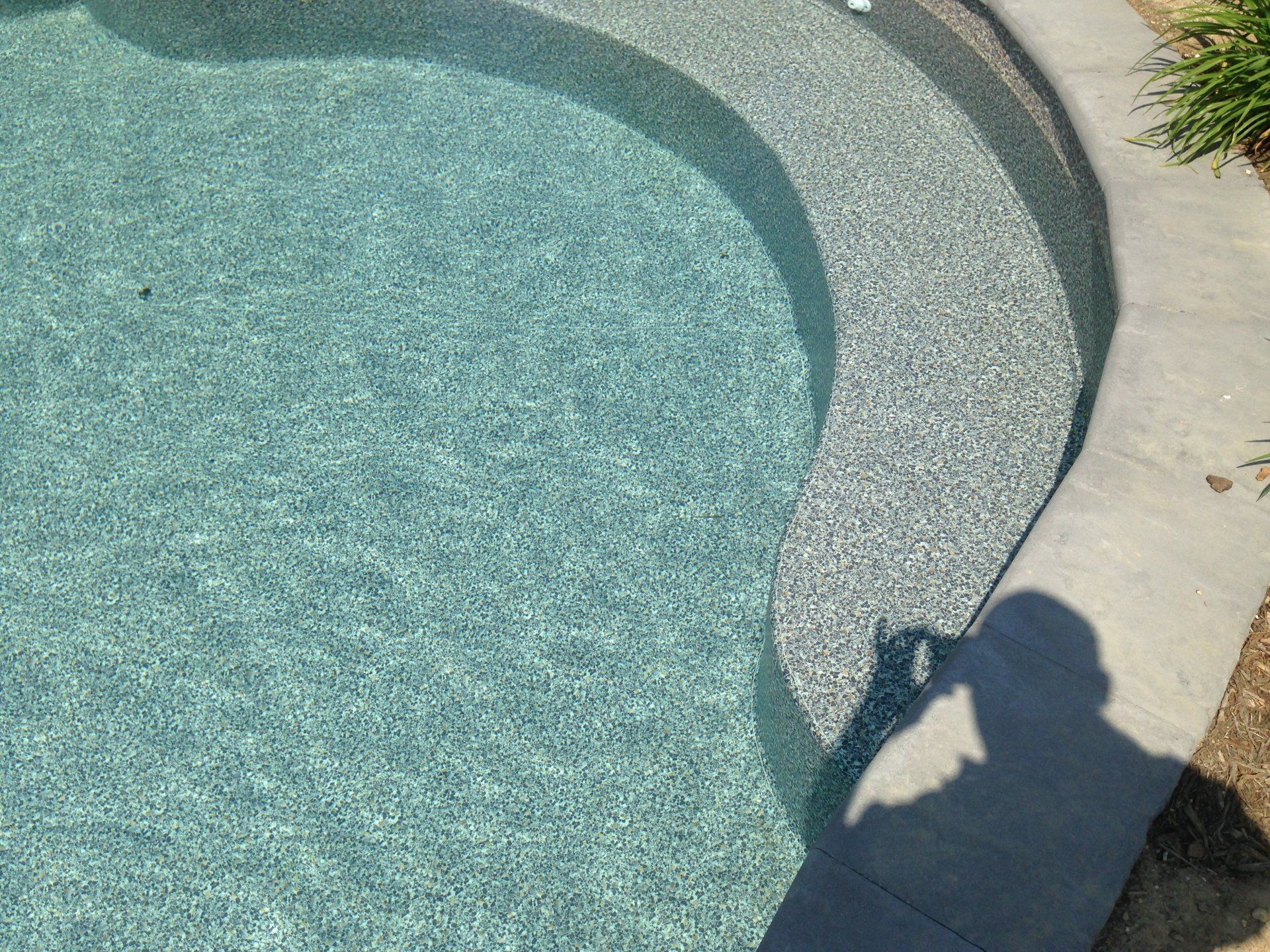 a shadow of a person is cast on the edge of a swimming pool