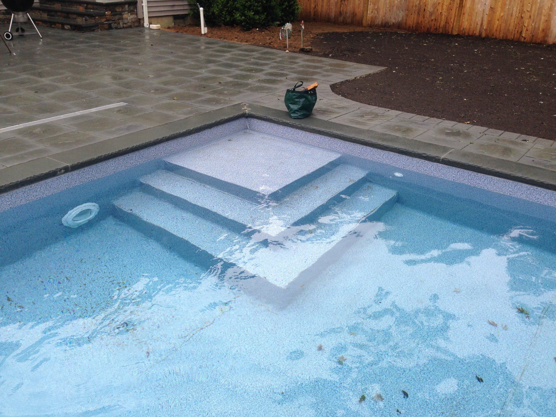 a green bag sits on the edge of a swimming pool