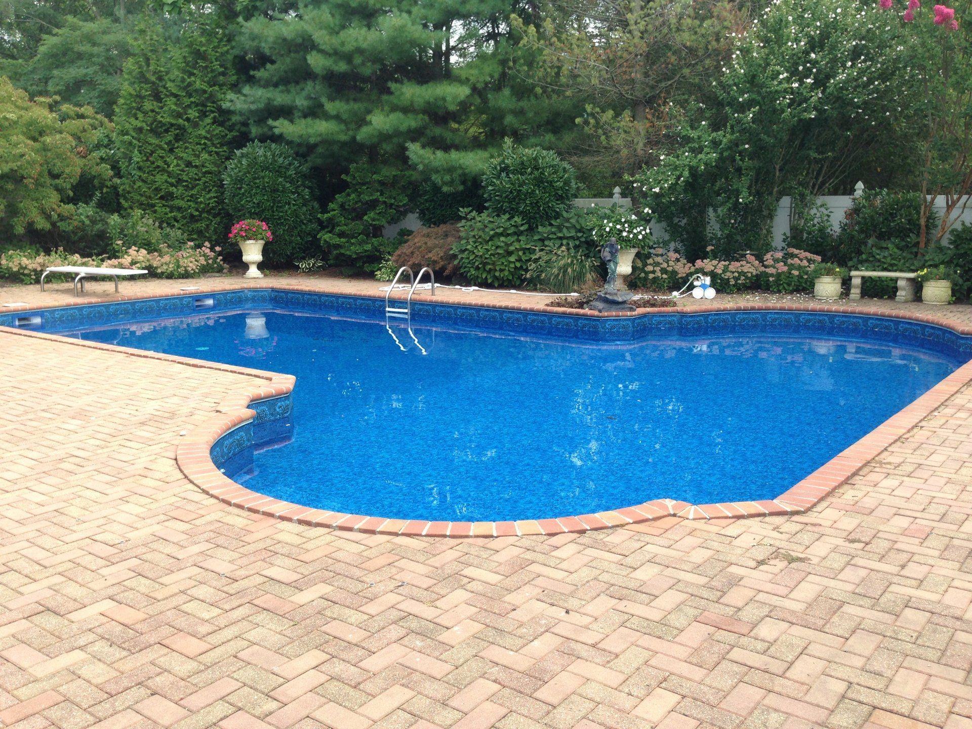 a large swimming pool surrounded by bricks and trees