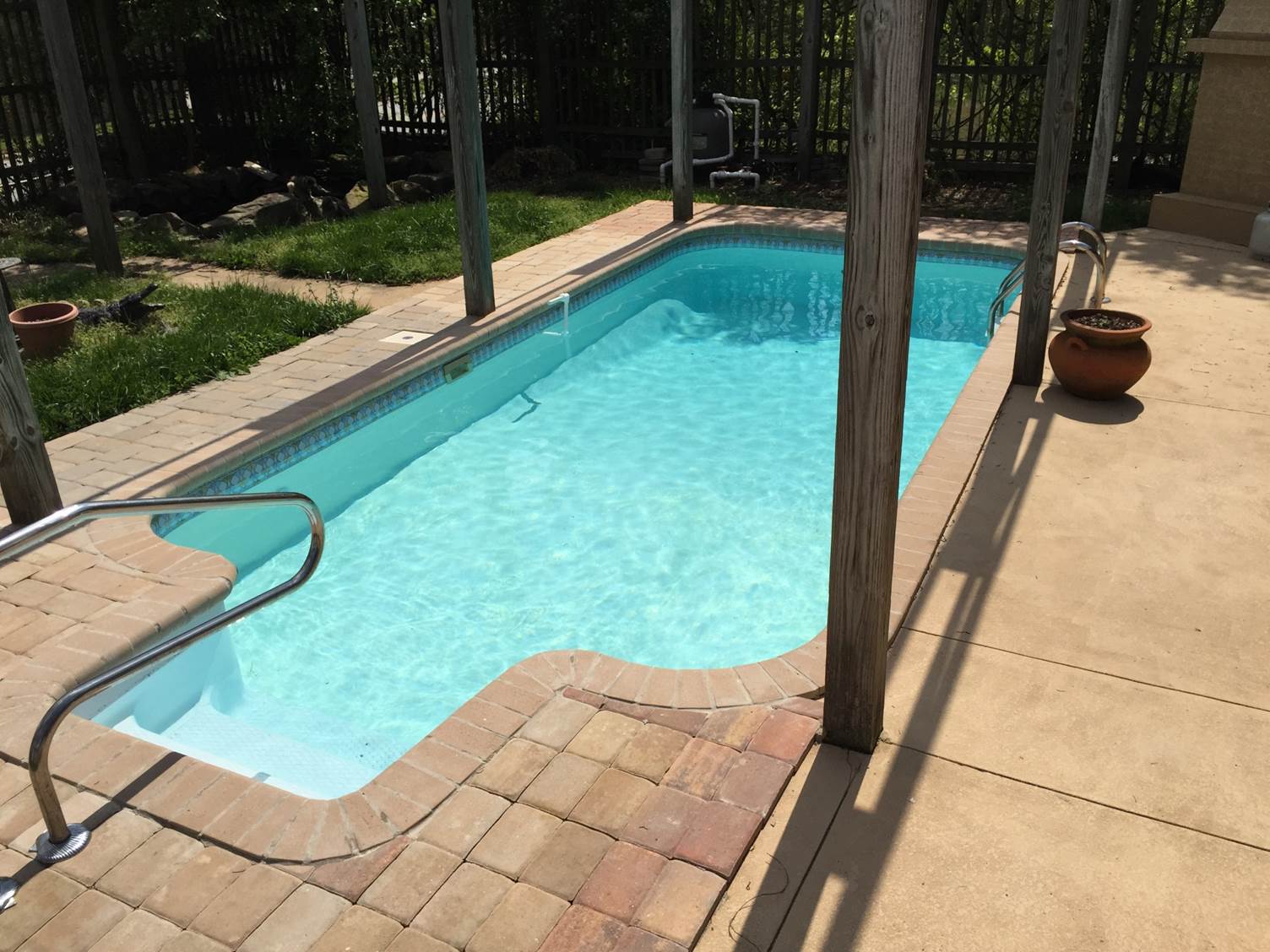 a small swimming pool is surrounded by bricks and a fence