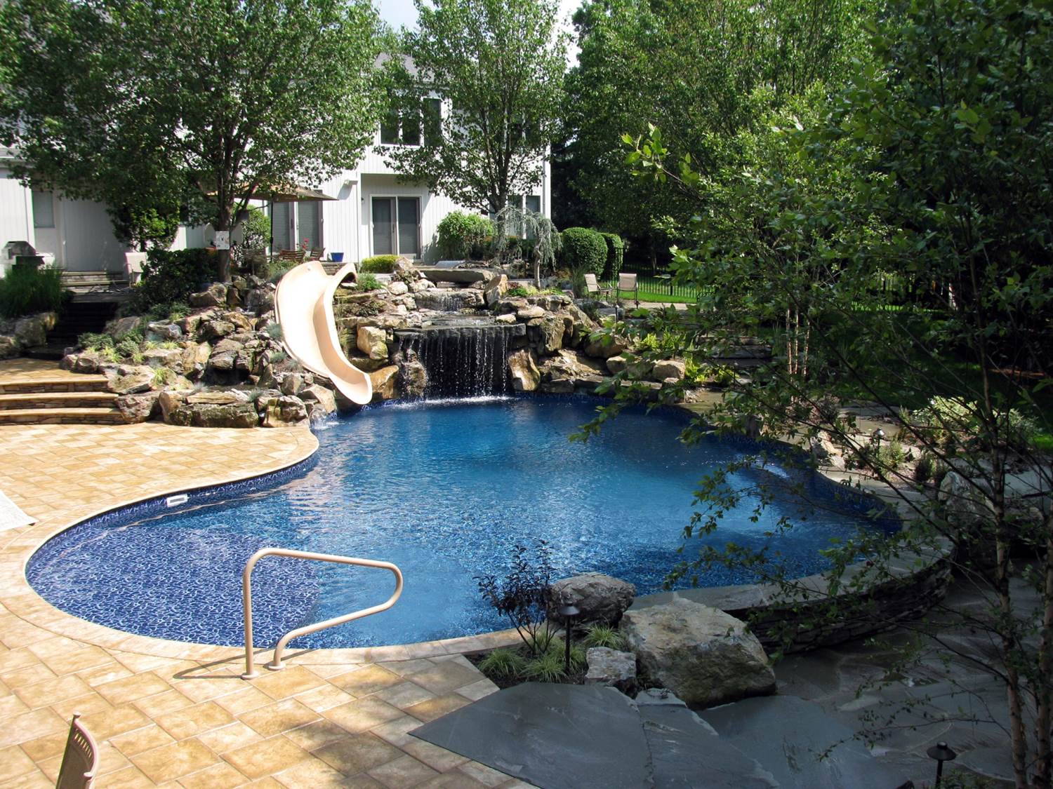 a large swimming pool with a water slide in the backyard