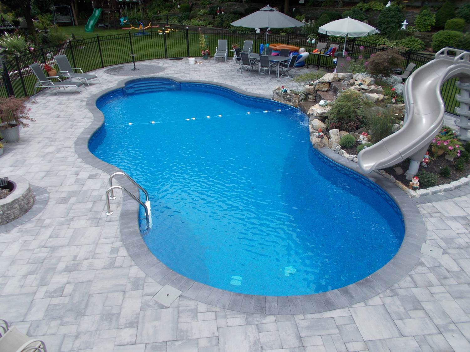 a large swimming pool with a slide in the backyard