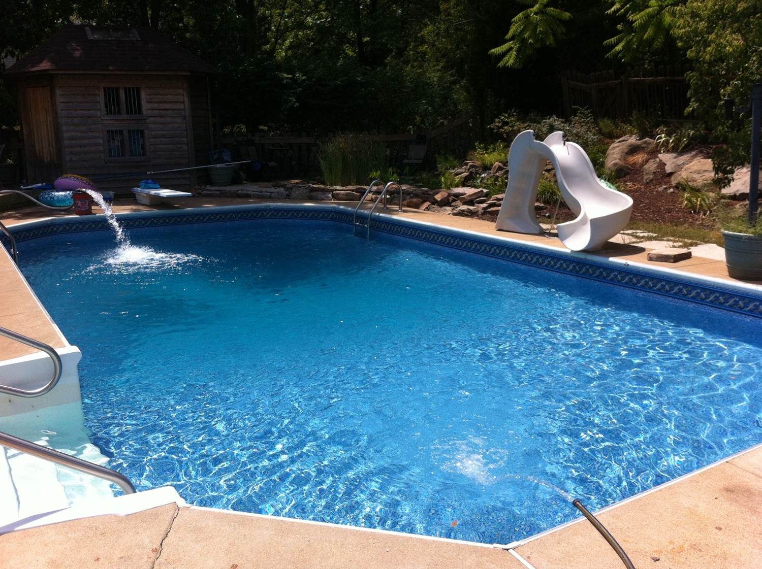 a large swimming pool with a slide in the backyard