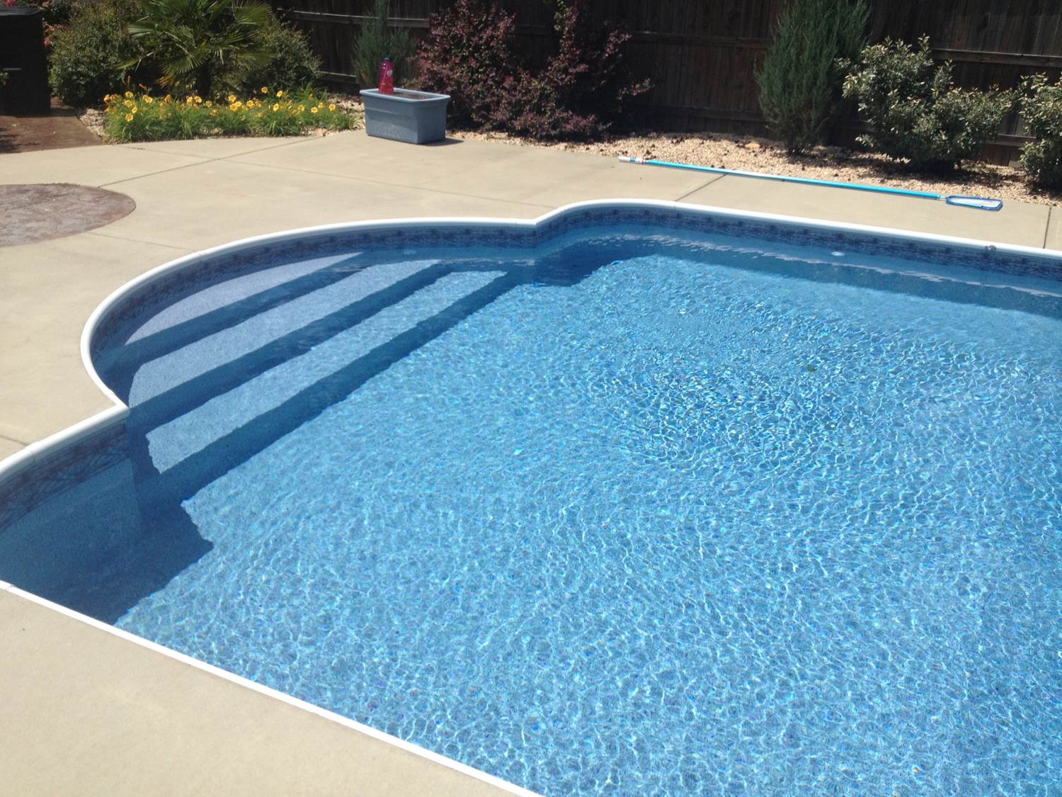 a swimming pool with stairs and a fence in the background
